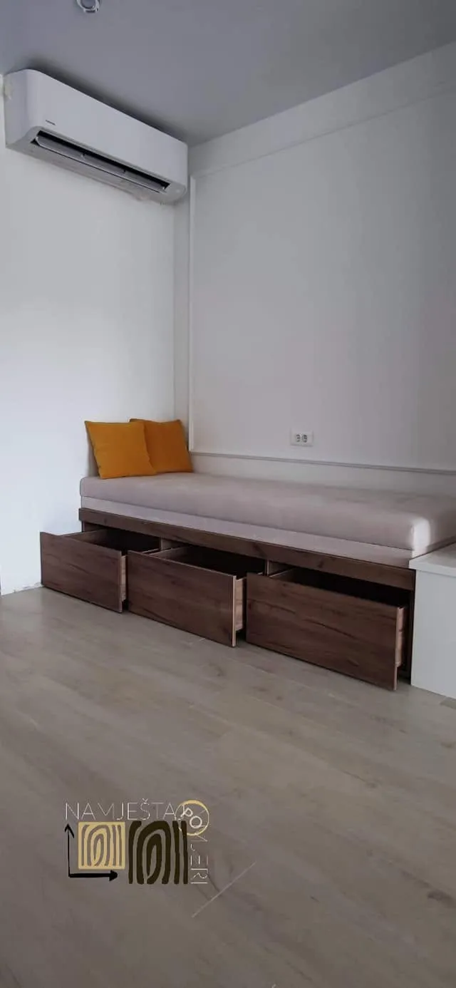 Klupa sa tapaciranim sjedištem uz zid